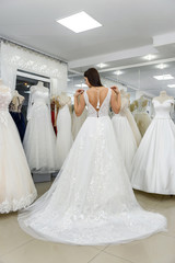 Naklejka premium Happy bride in wedding dress standing in salon