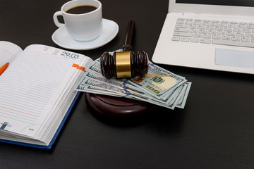 Judge gavel with dollar banknotes, laptop and coffee