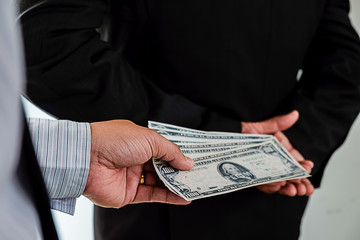 Businessman giving money while making deal to agreement a real estate contract and financial corporate.Bribery and corruption concept