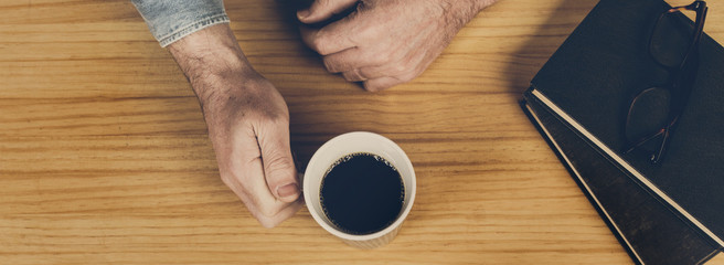 Hombre con taza de café y libros vista de arriba. Formato panorámico