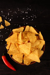 Mexican nachos in Wooden Bowl tortilla chips with chilli pepper and salt, top view and Black Background