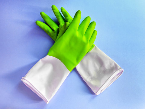 Green rubber protective gloves on the blue background. Early spring or regular cleanup.