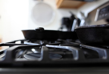 Fototapeta na wymiar Modern stainless steel gas stove with cast iron skillets in a home kitchen.