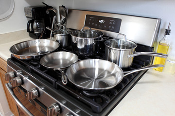 Modern gas stove with stainless steel cookware in a home kitchen.