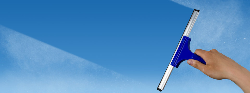 squeegee cleaning a dirty window, spring cleaning concept, blue sky with copy space