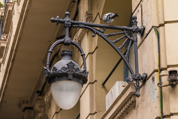 Wrought ornate hanging street light on the background of the urban historic building closeup, Barcelona, Spain