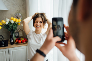 Happy loved couple are making the selfie with red apple in their new wooden kitchen.