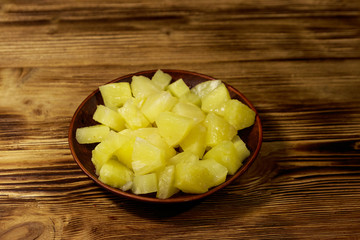 Canned pineapple pieces in ceramic plate on wooden table