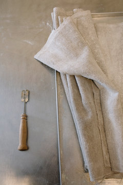 Artisan Bread Baking Essentials: Lame, Proofing Cloths, and Baking Tools on Metal Surface