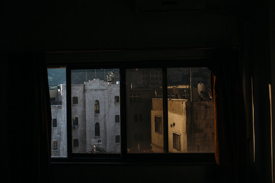 Dimly Lit Room View of Old City Buildings at Dusk Through a Window. Amman.