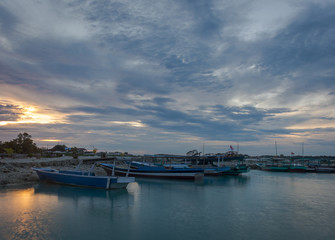 Fototapeta premium A fishing boat docked on the island of Harapan Island, Indonesia with a beautiful orange sunset behind