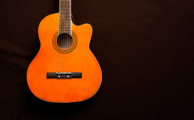 Six-string acoustic guitar on a dark brown background. Classical Spanish guitar. Musical instrument. Place for text.