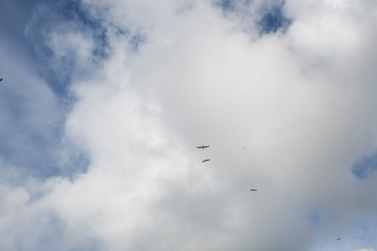Airplanes flying in formation through a cloudy blue sky