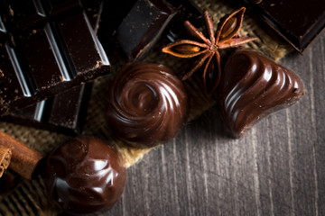 Assortment of dark, white and milk chocolate stack, chips. Chocolate and coffee beans on rustic wooden sacking background. Spices, cinnamon. Selective macro focus. Chocolates background. Sweets