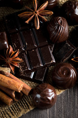 Assortment of dark, white and milk chocolate stack, chips. Chocolate and coffee beans on rustic wooden sacking background. Spices, cinnamon. Selective macro focus. Chocolates background. Sweets