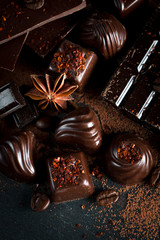 Assortment of dark, white and milk chocolate stack, chips. Chocolate and coffee beans on rustic wooden sacking background. Spices, cinnamon. Selective macro focus. Chocolates background. Sweets