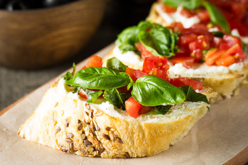 Tomato and cheese fresh made bruschetta. Italian tapas, antipasti with vegetables, herbs and oil on grilled ciabatta and baguette bread. Sandwich.