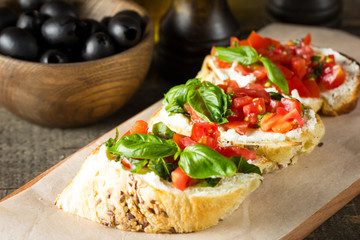 Tomato and cheese fresh made bruschetta. Italian tapas, antipasti with vegetables, herbs and oil on grilled ciabatta and baguette bread. Sandwich.