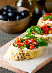 Tomato and cheese fresh made bruschetta. Italian tapas, antipasti with vegetables, herbs and oil on grilled ciabatta and baguette bread. Sandwich.