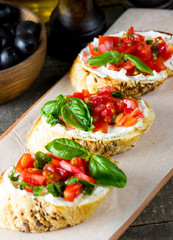 Tomato and cheese fresh made bruschetta. Italian tapas, antipasti with vegetables, herbs and oil on grilled ciabatta and baguette bread. Sandwich.
