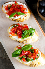 Tomato and cheese fresh made bruschetta. Italian tapas, antipasti with vegetables, herbs and oil on grilled ciabatta and baguette bread. Sandwich.