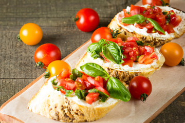 Tomato and cheese fresh made bruschetta. Italian tapas, antipasti with vegetables, herbs and oil on grilled ciabatta and baguette bread. Sandwich.