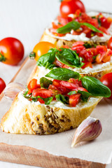 Tomato and cheese fresh made bruschetta. Italian tapas, antipasti with vegetables, herbs and oil on grilled ciabatta and baguette bread. Sandwich.