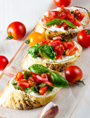 Tomato and cheese fresh made bruschetta. Italian tapas, antipasti with vegetables, herbs and oil on grilled ciabatta and baguette bread. Sandwich.