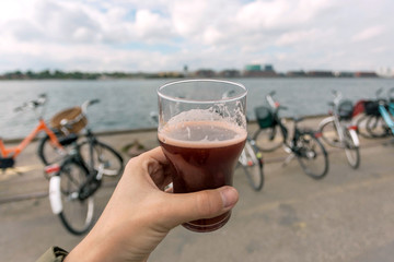 Riverbanks and hand with beer glass. Center of city Copenhagen, Denmark. Danish capital bicycles and fun time