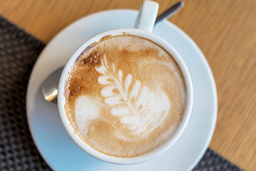 Cup of cappuccino with latte art. Beautiful foam, white cups.