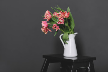 A bouquet of pink peony tulips in a white jug.