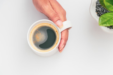 girl's hands holding coffee cup with plant flat lay top view