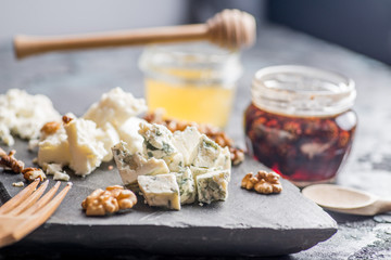 various cheeses on a plate with sauces and.confitures, honey and nuts