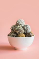 Homemade natural energy balls, vegan chocolate truffle with cacao, coconut on pink background. Healthy food for children, sweets substitute.