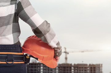 A female construction worker with safety helmet against city background