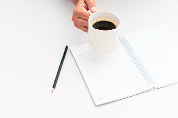 Woman hand holding cup of coffee open notebook Flat lay