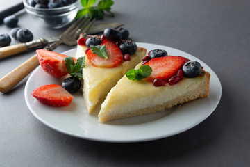Cheesecake slices in gray plate,with fresh berries and mint for dessert - healthy organic summer dessert pie cheesecake. Cheese cake.