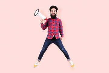 full length studio portrait of bearded crazy hipster man in glasses, jumping and shouting in...