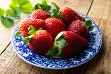 Fresh summer Strawberry in blue vintage plate on rustic wooden background with copy space. Close up berry, breakfast or healthy snack.