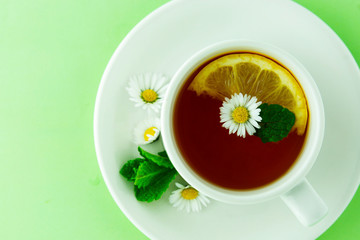 Cup of tea and chamomiles. herbal natural tea concept. White cup of tea with chamomile flowers.