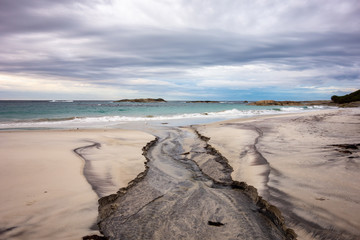 Wide angle photo of a dry wiver with a black sand on a beach in Western Australia