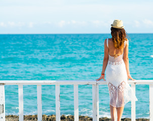 Young  woman in white dress, sea and bright sky in the background