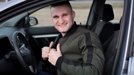 Attractive smiling happy young man in a car