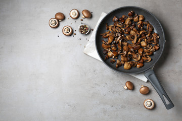 Frying pan of mushrooms on grey background, flat lay with space for text