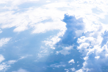 Aerial view of the blue skies and horizon with fluffy clouds and the earth below.