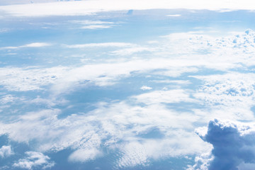 Fototapeta premium Aerial view of the blue skies and horizon with fluffy clouds and the earth below.