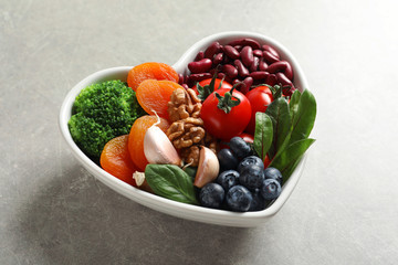 Bowl with products for heart-healthy diet on grey table