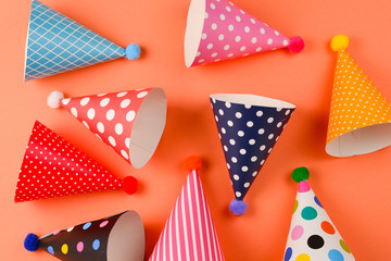 Obraz premium Colorful birthday caps on orange background. Top view.