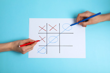 Women playing tic-tac-toe on color background, top view. Victory concept