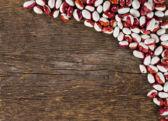 Spotted beans on a background of rough wooden texture.